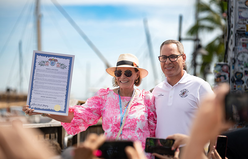 Restaurateur and author Lucy Buffett, sister of the late musical icon Jimmy Buffett, accepts a proclamation designating Jimmy Buffett Day from Key West City Commissioner Donie Lee on Friday, Aug. 29, in Key West, Fla. Held outside the singer-songwriter’s Shrimpboat Sound recording studio, the proclamation ceremony kicked off the four-day Just a Few Friends festivities honoring Buffett’s legacy on the island that inspired his signature sound. (Photo credit: Nick Doll, Just a Few Friends)